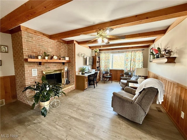 living room with a brick fireplace, wooden walls, visible vents, and a wainscoted wall