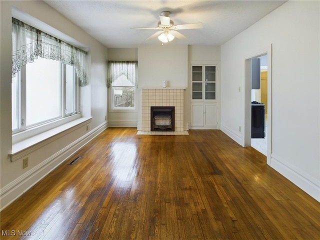 unfurnished living room with ceiling fan, dark wood-type flooring, and a fireplace