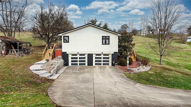 view of side of property with concrete driveway, a lawn, an attached garage, and stairs