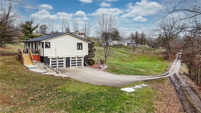 view of side of home with concrete driveway, a lawn, an attached garage, and stairs