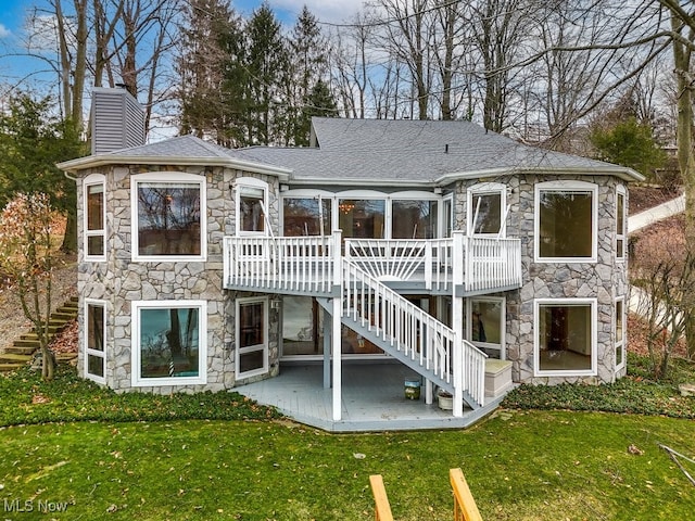 rear view of property with a wooden deck and a lawn