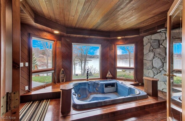 interior space featuring hardwood / wood-style flooring, wooden walls, a hot tub, and wooden ceiling