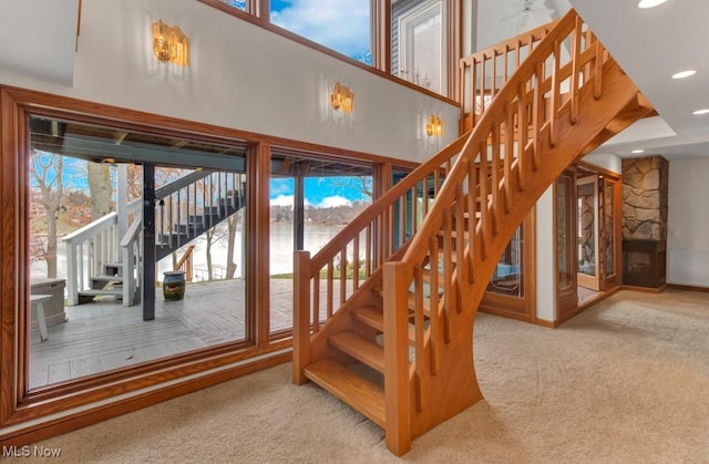 stairway with a high ceiling and carpet floors