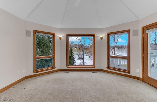 spare room featuring light colored carpet and lofted ceiling