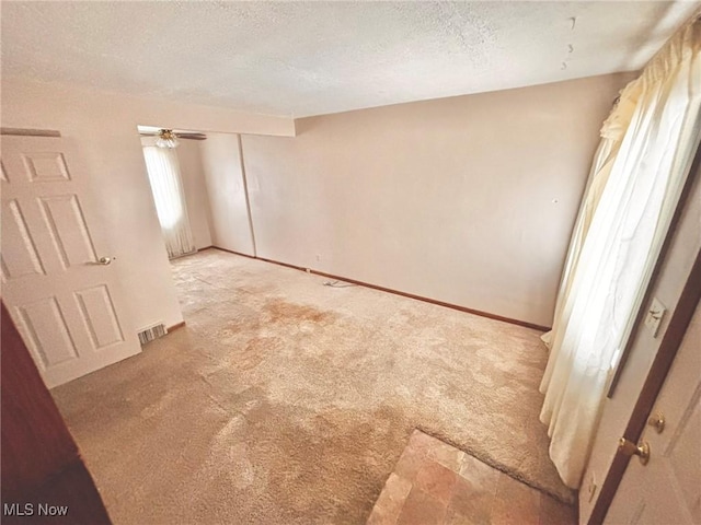 unfurnished room with light carpet and a textured ceiling