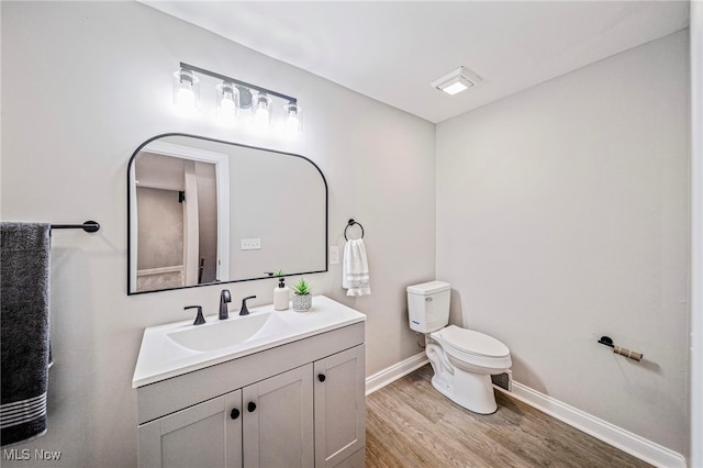 bathroom featuring wood-type flooring, toilet, and vanity