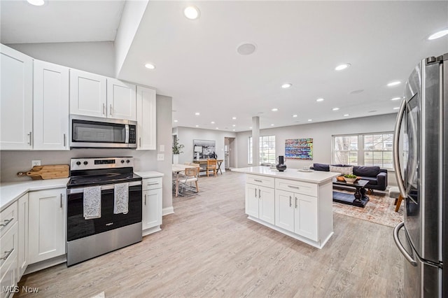 kitchen with a wealth of natural light, stainless steel appliances, light hardwood / wood-style floors, and white cabinets