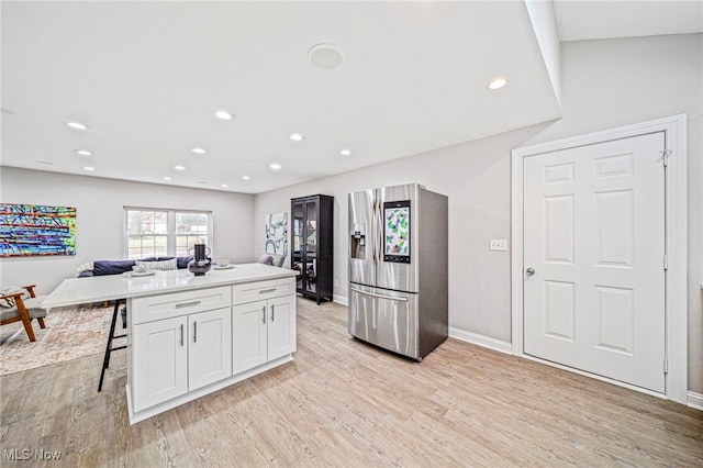 kitchen with white cabinetry, stainless steel fridge, and light hardwood / wood-style floors