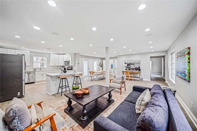 living room featuring french doors, sink, and light hardwood / wood-style flooring