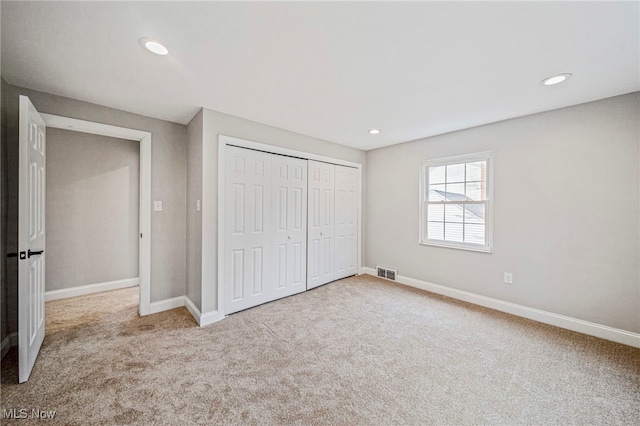 unfurnished bedroom featuring light carpet and a closet