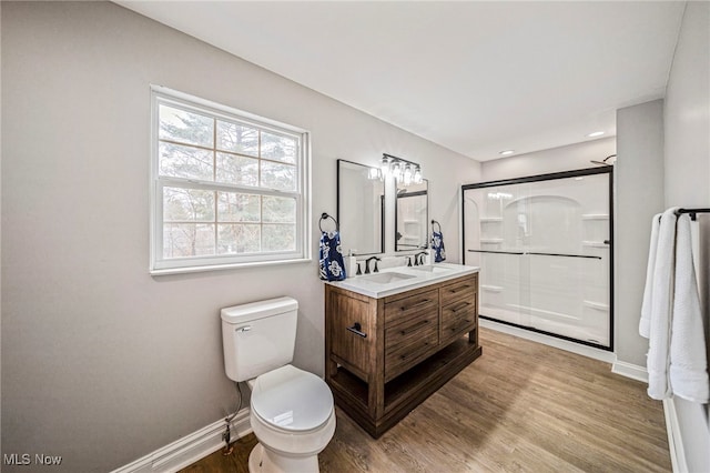 bathroom featuring wood-type flooring, toilet, a shower with shower door, and vanity