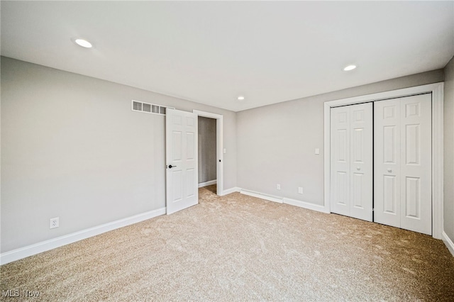 unfurnished bedroom with light colored carpet and a closet