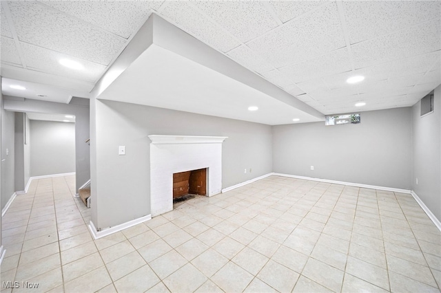 basement with a drop ceiling and light tile patterned floors