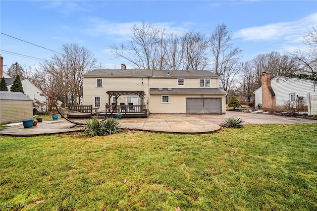 back of property with a garage, a pergola, a lawn, and a deck