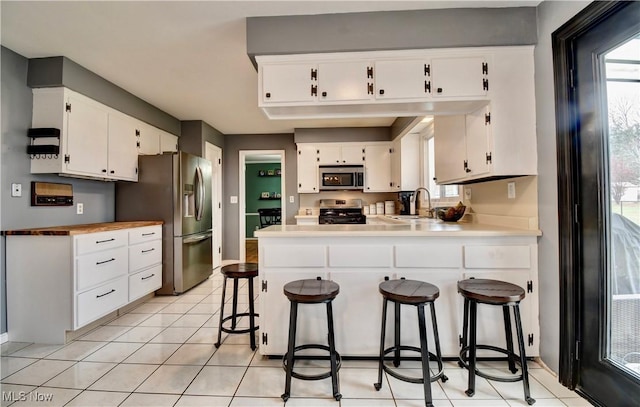 kitchen with white cabinetry, a breakfast bar area, kitchen peninsula, and appliances with stainless steel finishes