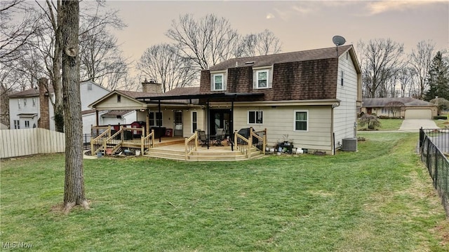 back house at dusk featuring central AC unit, a lawn, and a deck