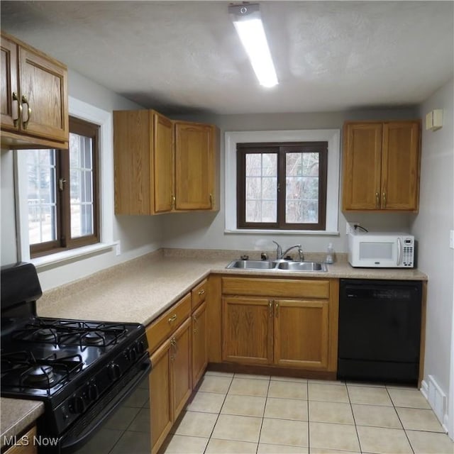 kitchen with sink, light tile patterned floors, and black appliances