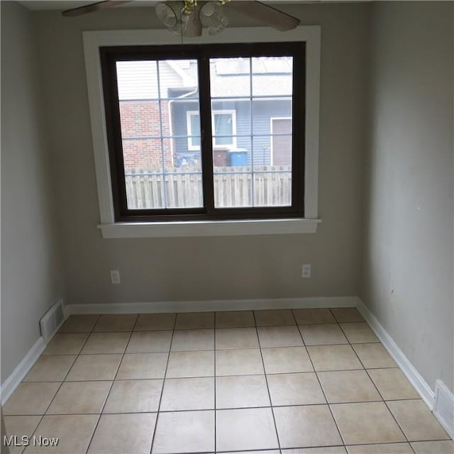 tiled spare room featuring plenty of natural light and ceiling fan