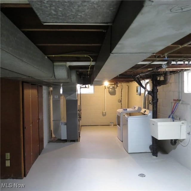 basement featuring washer and dryer, sink, and heating unit