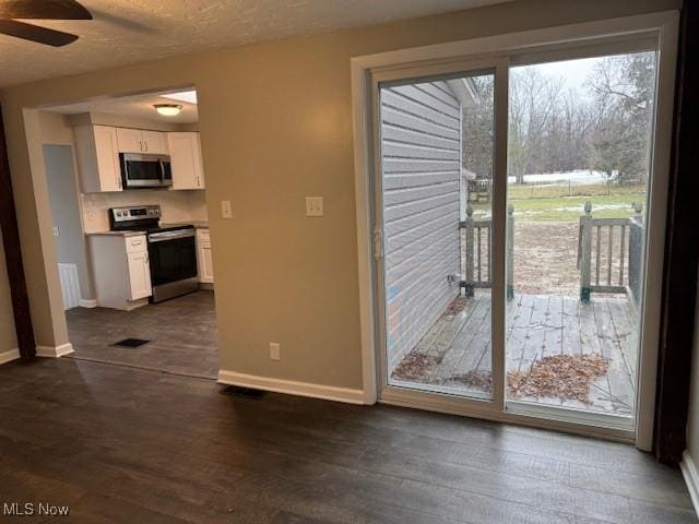 kitchen featuring white cabinetry, dark hardwood / wood-style flooring, ceiling fan, stainless steel appliances, and a textured ceiling