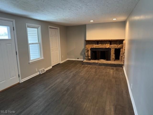 unfurnished living room with dark hardwood / wood-style floors, a fireplace, and a textured ceiling