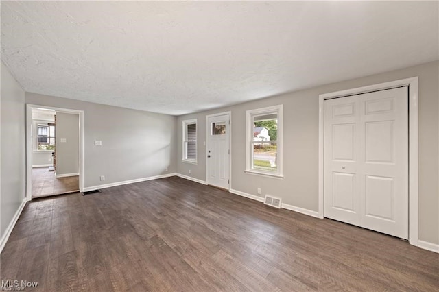 unfurnished living room featuring dark hardwood / wood-style floors and a textured ceiling