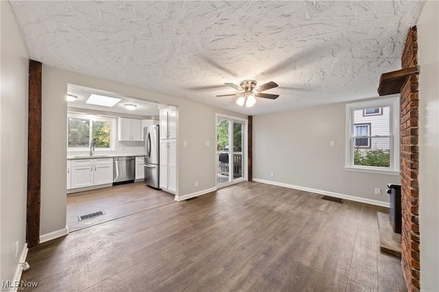 unfurnished living room featuring dark hardwood / wood-style flooring, a textured ceiling, and a healthy amount of sunlight