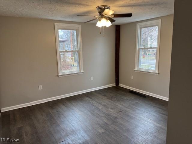 unfurnished room featuring dark hardwood / wood-style flooring, a textured ceiling, and a wealth of natural light