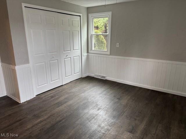 unfurnished bedroom featuring dark hardwood / wood-style floors and a closet