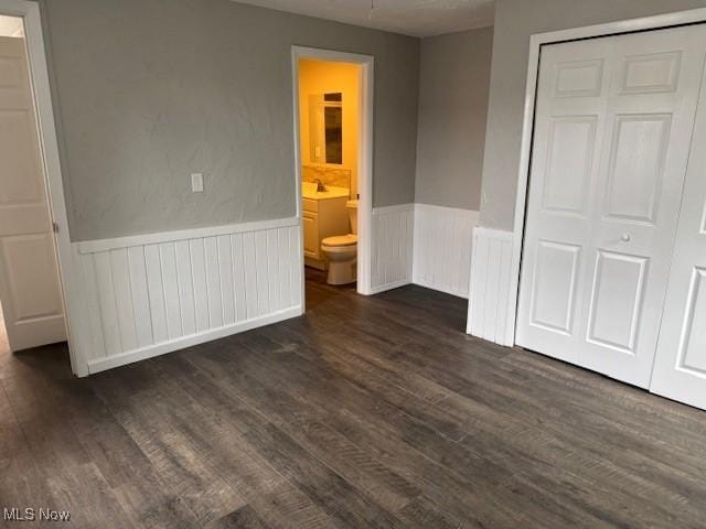 unfurnished bedroom featuring ensuite bath, dark hardwood / wood-style floors, sink, and a closet