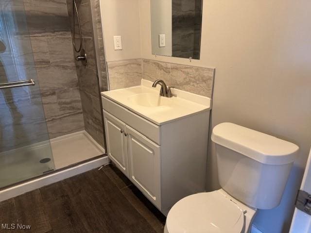 bathroom with wood-type flooring, toilet, vanity, and walk in shower