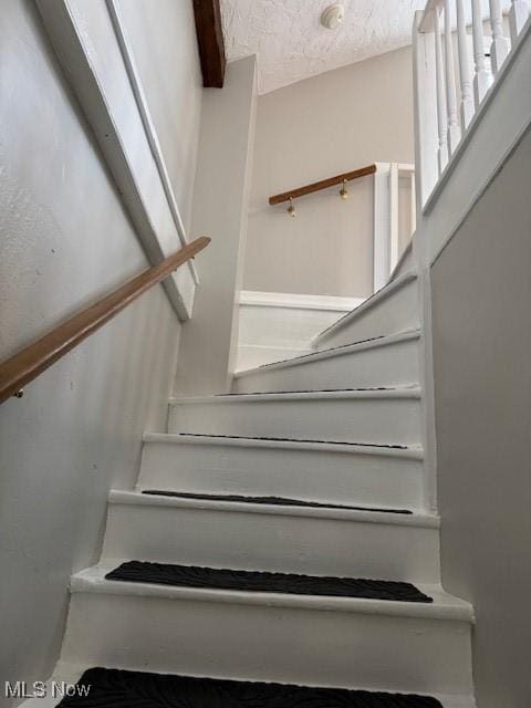 stairway featuring a textured ceiling