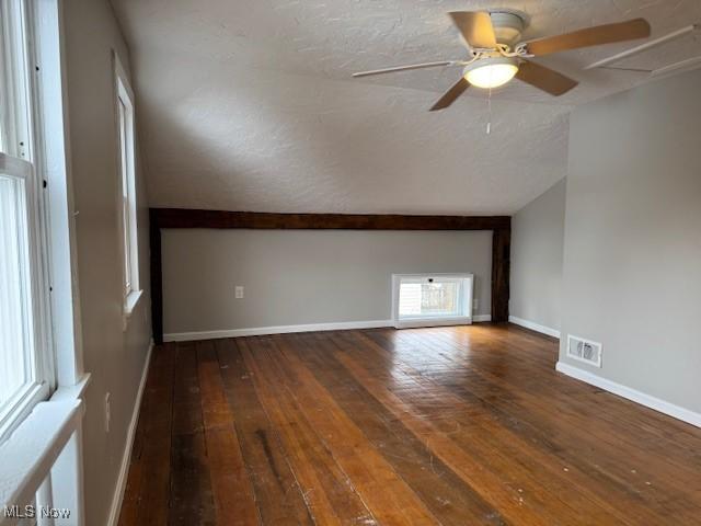 interior space with a textured ceiling, dark wood-type flooring, ceiling fan, and vaulted ceiling