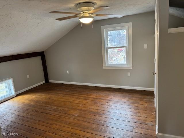 additional living space featuring ceiling fan, lofted ceiling, dark hardwood / wood-style flooring, and a textured ceiling