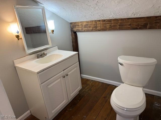 bathroom featuring toilet, wood-type flooring, vaulted ceiling, a textured ceiling, and vanity