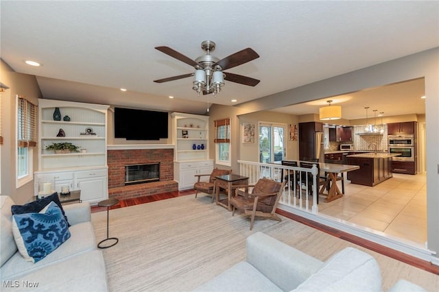 tiled living room featuring a brick fireplace and ceiling fan