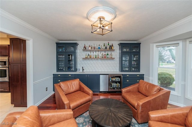 bar with backsplash, crown molding, blue cabinetry, and beverage cooler