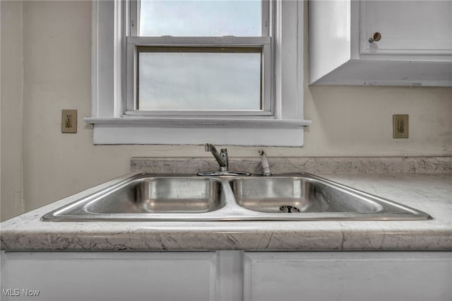 interior details featuring white cabinetry and sink