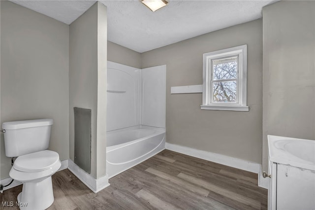 full bathroom with wood-type flooring, toilet, vanity, and a textured ceiling