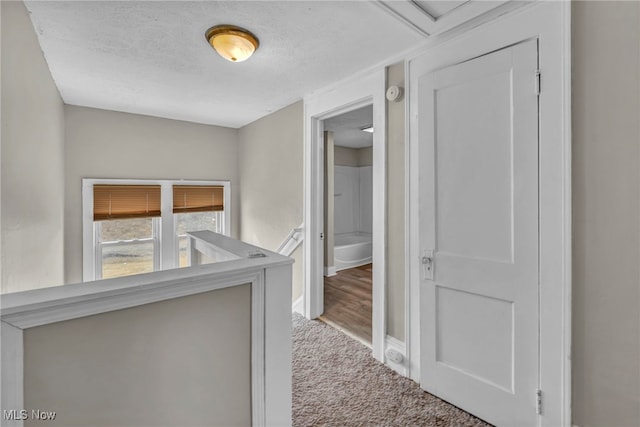 hallway with a textured ceiling and carpet