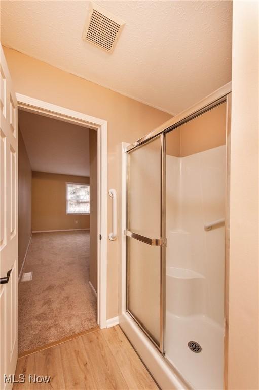 bathroom featuring hardwood / wood-style floors, a textured ceiling, and walk in shower