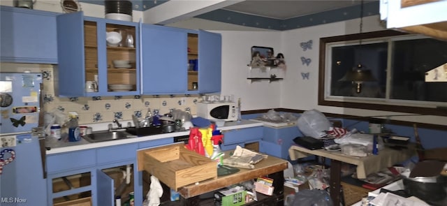 kitchen featuring blue cabinetry, sink, and stainless steel fridge