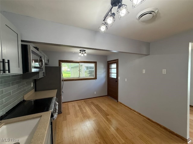 950 Donmar Ln, Boardman, OH 44511 - kitchen featuring stainless steel microwave, backsplash, light wood-style floors, and light countertops