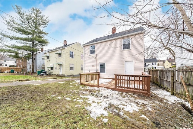 back of house featuring a lawn and a deck