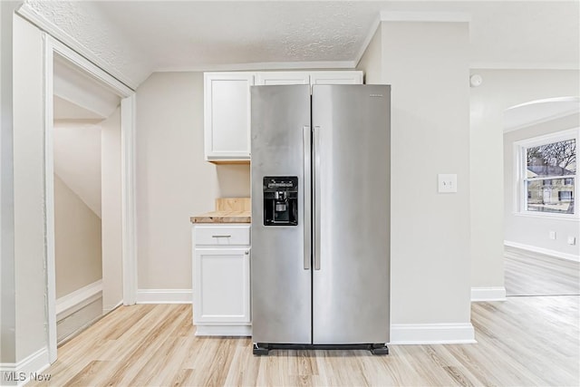 kitchen featuring vaulted ceiling, white cabinetry, stainless steel fridge, a textured ceiling, and light hardwood / wood-style flooring