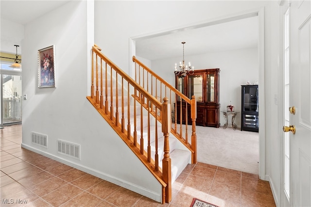 stairway with an inviting chandelier and tile patterned flooring