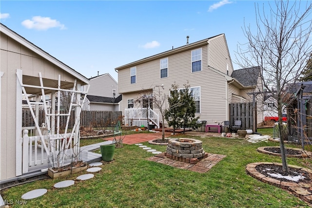 rear view of property featuring a patio, a fire pit, and a lawn