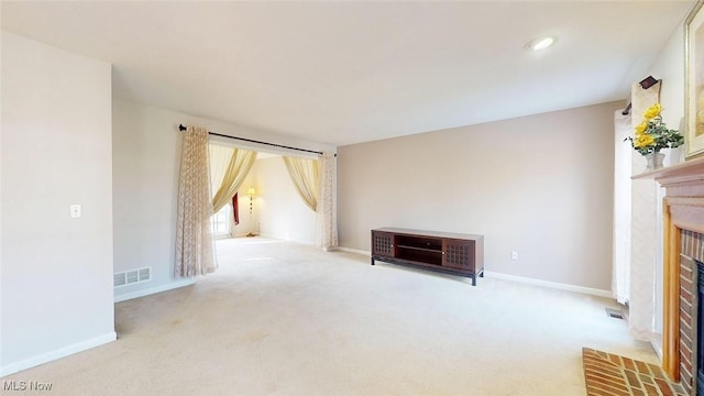 unfurnished living room featuring light carpet and a fireplace