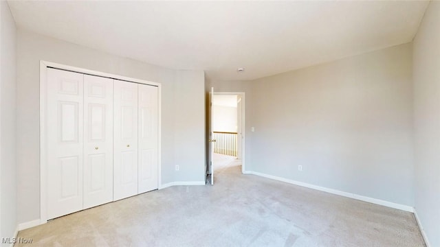 unfurnished bedroom with light carpet and a closet