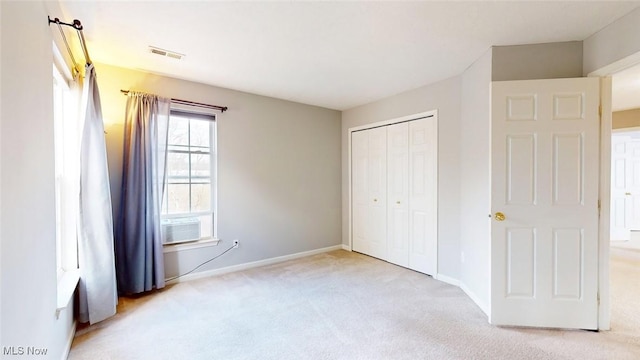 unfurnished bedroom with cooling unit, light colored carpet, and a closet